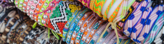 Colorful handmade bracelets made of beads and thread on the counter of gift shop