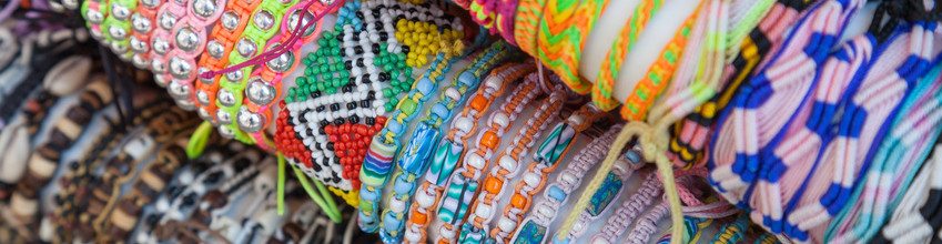 Colorful handmade bracelets made of beads and thread on the counter of gift shop